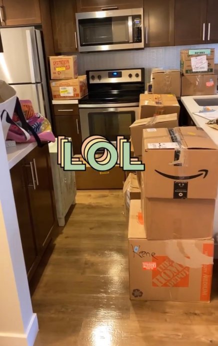 The pic shows many boxes of various sizes in front of kitchen cabinets and appliances